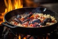 coals and flames under cast iron pan with risotto cooking