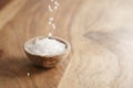 Coarse sea salt falling into wooden bowl on table Royalty Free Stock Photo