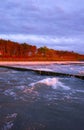 Coast of baltic sea with wooden breakwaters at sunset