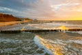 Coast of baltic sea with wooden breakwaters at sunset