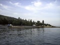 The coast of a calm sea with buildings and greenery on a cloudless day