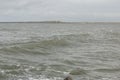 Coast line at Thyboron on the Danish west coast, clouds in the sky, waves in the sea, white foam splashes, rocks Royalty Free Stock Photo