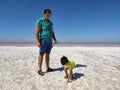 The coast of the salty Pink Lake in Crimea. A man in blue breeches with a camera and a little boy. Father and son. The boy bent Royalty Free Stock Photo