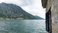Coast town under the big mountains of Montenegro in Kotor bay. Old house abandoned in the sea. Cloudy day in small village and Royalty Free Stock Photo