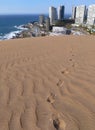 Coastal city behind sand dune with trace of footprints on it Royalty Free Stock Photo