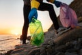Coastal cleaning. Volunteer pick-up plastic bottle and holding a garbage bag, bottom view. The concept of environmental