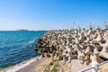 Coastal concrete breakwaters against blue ocean with distant industrial structures Royalty Free Stock Photo