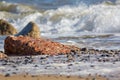 Coastal erosion. Destructive wave action. Focus on eroded concrete block.