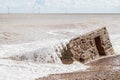 Coastal erosion. Wave action engulfing WW2 concrete ant-invasion structure.