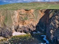 Coastal land loss caused by land erosion and slippage into the sea.