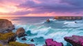 Coastal rocks and cliffs with waves crashing under a dramatic, colorful sky