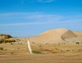 Coastal sand dunes of the Sahara Desert with tire tracks and barbed wire fence against blue sky Royalty Free Stock Photo