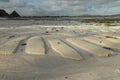 The coastal strip at low tide. A desert area with wet sand, a wavy relief runs along it. Close up. Relief of the sand beach of the