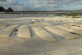 The coastal strip at low tide. A desert area with wet sand, a wavy relief runs along it. Close up. Relief of the sand beach of the