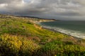 Coastal view of Laguna Beach, California under dramatic clouds at golden hour from Crystal Cove State Park