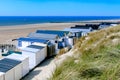 Coastal view with vacation homes, dunes, empty beach, blue sea and clear sky.