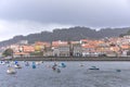 Coastal village in the background and fishing boats in the sea in the foreground. Galicia, Spain