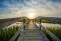 Sunset over coastal waters with a very long wooden boardwalk Royalty Free Stock Photo