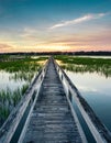 Vertical view of a beautiful sunset over coastal waters with a very long wooden boardwalk pier in the center during a colorful sum Royalty Free Stock Photo