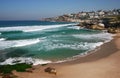 Idyllic and amazing seaside landscape of beach with white rushing sea waves, and hillside buildings in Sydney, Australia
