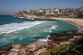 Idyllic and amazing seaside landscape of jagged shore with rocks, white rushing sea waves, hillside buildings in Sydney, Australia