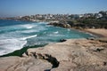 Idyllic and amazing seaside landscape of jagged shore with rocks, white rushing sea waves, hillside buildings in Sydney, Australia