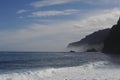 Coastline of an island with high cliffs and blue sea and waves and blue sky with clouds Royalty Free Stock Photo