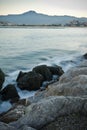 Coastline rocks in satin soft atlantic ocean, mountain trois couronnes at sunset in long exposure, basque country, france