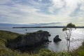 Scenic Coastline View: Lighthouse on Horizon Under Blue Sky