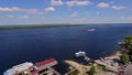 coastline of wide river with boat dock, aerial view at summer, big motorship is moving on central of river