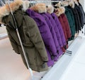 Coats with fur on hood hanging on clothes rack
