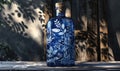 Cobalt blue glass bottle with botanical illustrations on background with textured shadow Royalty Free Stock Photo