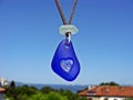 Cobalt blue sea glass sun catcher with engraved heart hanging on blue sky background. Beach cottage decor concept Royalty Free Stock Photo