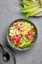 Cobb Salad in gray matte bowl on concrete backdrop. American cuisine dish with tomatoes, chicken, bacon, eggs, cheese, avocado and