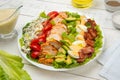 Cobb salad in a white salad bowl with ingredients on an old rustic white wooden table. Royalty Free Stock Photo