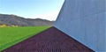 A cobbled road along an endless concrete wall in a green meadow in a mountain valley. Empty and no one. Complete abstraction. 3d