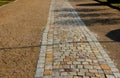 Cobbled strip of beige brown cobblestone stones. around is a park gravel road of the castle`s honorary courtyard. Centrally symmet Royalty Free Stock Photo