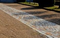 Cobbled strip of beige brown cobblestone stones. around is a park gravel road of the castle`s honorary courtyard. Centrally symmet Royalty Free Stock Photo