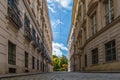 A cobbled Viennese street near to the university, with white clouds and blue sky above. Street light cables run through the frame