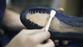 Cobbler applying glue to a blue shoe sole with a brush, close up