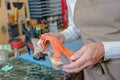 Cobbler holding orange wedge heeled shoe