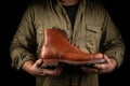 Cobbler holding pair of brown leather shoe