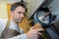 Cobbler holding sole shoe against rotating wheel