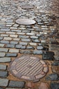 Cobblestone road with cast-iron sewer hatches Royalty Free Stock Photo