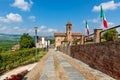 Cobblestone street along brick wall and parish church on background in Grinzane Cavour, Italy. Royalty Free Stock Photo