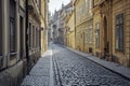 A cobblestone street flanked by classic, colorful buildings under a bright sky, exuding an old-world, charming atmosphere