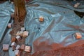 Cobblestones weigh down a plastic sheet that is covering a paving construction site Royalty Free Stock Photo