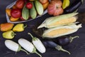 cobs of sweet corn, cucumbers, yellow and red tomatoes, peppers and white and black eggplants