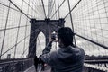 Coceptual cinematic photography tourist man taking picture with cell phone on Brooklyn Bridge, New York City USA. Royalty Free Stock Photo