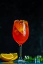 Cocktail aperol spritz in big wine glass with water drops on dark background. Summer alcohol cocktail with orange slices. Italian